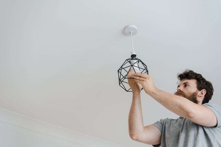 Man installing a bulb into a new ceiling light fixture